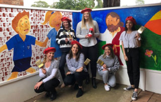 Our Lady of Mt Carmel Catholic Primary School Mt Pritchard teachers stand in front of their school art mural.