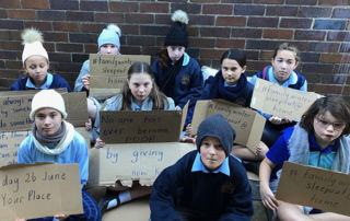 St Patrick’s Catholic Primary School Sutherland students with placards highlighting the importance of helping people who are experiencing or at risk of homeless